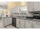 Bright kitchen featuring white cabinets, gray countertops, and a window with plants, creating a cozy atmosphere at 6887 King Arthur Dr., Myrtle Beach, SC 29588