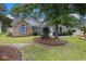 Attractive brick home with blue shutters, a well-manicured lawn, and mature trees providing ample shade at 7007 Blade Beak Ln., Myrtle Beach, SC 29588