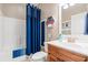 Bathroom featuring a wooden vanity, modern fixtures, white toilet and tub with blue curtain at 1025 Limpkin Dr., Conway, SC 29526