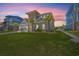 Eye-catching elevation showcases verdant lawn, palm trees, and architectural design elements set against colorful evening sky at 109 Serenity Point Dr., Little River, SC 29566