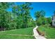 Landscaped backyard with a winding pathway and lush greenery leading to a lake at 112 Blue Gull Dr., Conway, SC 29526