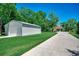 View of a detached metal garage, driveway, and house with a yard and abundant mature trees at 112 Blue Gull Dr., Conway, SC 29526
