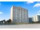 Exterior view of a high-rise condominium building on a sunny day, located directly on a sandy beach at 1207 S Ocean Blvd. # 20109, Myrtle Beach, SC 29577