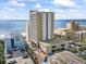 Aerial view of a beige high-rise condominium tower, parking lot, a pool, and surrounding buildings with an ocean view at 1207 S Ocean Blvd. # 20109, Myrtle Beach, SC 29577