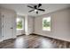 Sun-filled bedroom with wood-look flooring, ceiling fan, and two windows offering natural light at 142 Temple Dr., Aynor, SC 29511