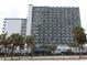 Exterior view of a multi-story building with palm trees and a parking lot in front at 2001 S Ocean Blvd. # 721, Myrtle Beach, SC 29577
