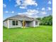 Backyard view of a home with gray siding, a covered porch, and a large green lawn at 2599 Woodcreek Ln., Conway, SC 29527