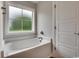 Bathroom featuring a soaking tub under a frosted window, accompanied by a paneled door at 2599 Woodcreek Ln., Conway, SC 29527