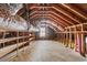 Unfinished attic space featuring wooden beams, shelving, and a window at 401 S Nichols St., Nichols, SC 29581