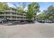 Condo exterior with white railings on balconies, trees, and parking lot view under a blue sky at 415 Ocean Creek Dr. # 2388, Myrtle Beach, SC 29572