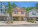 Charming raised beach house with yellow siding, red shutters, and a red roof situated between two other beach houses at 4319 Grande Harbour Blvd., Little River, SC 29566