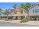 Three beautiful beach homes elevated above ground level and located on a street with lush trees and blue skies at 4319 Grande Harbour Blvd., Little River, SC 29566