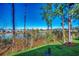 Backyard featuring lush green lawn, tall trees, and a lake with a glimpse of neighborhood homes across the water at 4486 Little River Inn Ln. # 2106, Little River, SC 29566