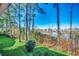 Backyard view showing lush lawn, mature trees, and tranquil lake with neighboring houses in the distance at 4486 Little River Inn Ln. # 2106, Little River, SC 29566