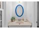 Bright half bath featuring a blue framed oval mirror, beige counter, and white walls at 515 River Rd., Conway, SC 29526
