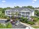 A three-story condo building with white railings, palm trees, and a parking lot in a sunny setting at 5801 Oyster Catcher Dr. # 332, North Myrtle Beach, SC 29582