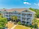 Three-story condo building featuring private balconies, lush landscaping, and convenient exterior staircases at 6203 Catalina Dr. # 1333, North Myrtle Beach, SC 29582