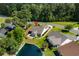 Aerial view showcasing a home with landscaping backing up to the lake in a lush, green neighborhood at 675 Vermillion Dr., Little River, SC 29566