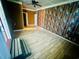 Living room featuring light wood laminate floors, brick accent wall, ceiling fan, and three points of entry at 704 W Alder St., Andrews, SC 29510