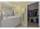 Bright bathroom featuring double sink vanity, large mirror, and walk-in closet for ample storage at 77 Redwing Ct., Pawleys Island, SC 29585