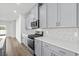 Open kitchen features stainless appliances, stone backsplash, quartz counters and gray cabinets at 8253 Vibrant Loop, Longs, SC 29568