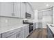 Close-up of kitchen with stainless appliances, stone backsplash, quartz counters and gray cabinets at 8253 Vibrant Loop, Longs, SC 29568
