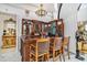 An ornate custom-built wooden bar features stained-glass, statue accents, and three barstools underneath a chandelier at 123 Pioneer Loop, Georgetown, SC 29440