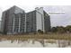 Exterior shot of the condominium building at Bluewater Resort with beach vegetation in the foreground at 2001 S Ocean Blvd. # 1504, Myrtle Beach, SC 29577