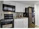 Compact kitchen featuring white cabinets, granite countertops, and black appliances, optimizing space and functionality at 2001 S Ocean Blvd. # 1504, Myrtle Beach, SC 29577