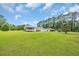 Large backyard showing the expansive lawn, the rear of the house, an outdoor garage and many surrounding trees at 203 Warbler St., Georgetown, SC 29440