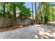 A partially shaded backyard with a privacy fence, some trees, and a parking pad at 250 Nature Trail, Little River, SC 29566