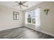 A bright bedroom with woodgrain floors, a ceiling fan, and a window with sheer curtains at 278 Carolina Crossing Blvd., Little River, SC 29566