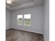 Bedroom with tray ceiling, ceiling fan, wood-look flooring, and view of backyard through windows at 307 Dunlin Pl, Conway, SC 29526