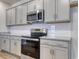 Close up of stainless steel oven and microwave, granite countertops, gray cabinets, and white subway tile backsplash at 307 Dunlin Pl, Conway, SC 29526
