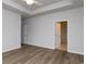Main bedroom with tray ceiling, wood-look floors, view of bathroom, and two entry doors at 307 Dunlin Pl, Conway, SC 29526