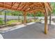 A covered patio features a concrete floor and a wooden structure with an orange metal roof in the landscaped backyard at 340 Boxcar Dr., Longs, SC 29568