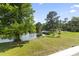 Scenic backyard featuring a tranquil pond surrounded by lush greenery and mature trees on a sunny day at 417 Grain Field Dr., Georgetown, SC 29440