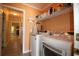 Functional laundry room with modern washer and dryer, storage shelving, and stylish orange paint at 513 Westham Dr., Murrells Inlet, SC 29576