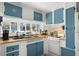Bright kitchen featuring blue cabinets, white appliances, and beach-themed decor for a coastal feel at 6001 - 1842 S Kings Hwy., Myrtle Beach, SC 29575