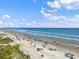 Wide sandy beach featuring various beachgoers, colorful umbrellas, and scenic ocean views at 6309 N Ocean Blvd. # 14 E, North Myrtle Beach, SC 29582