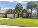 Well-maintained brick home featuring a lush lawn, mature trees, and a spacious two-car garage at 806 Compass Point Dr., North Myrtle Beach, SC 29582