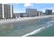Aerial view of the beach featuring ocean view with swimmers and vacationers, sunny blue skies, and condominiums at 920 N Waccamaw Dr. # 2102, Murrells Inlet, SC 29576