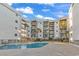Multi-story condo building showcasing poolside access and balconies with views, surrounded by palm trees at 1310 N Waccamaw Dr. # 208, Garden City Beach, SC 29576
