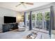 Bright living room with a television, comfortable chair, neutral carpet, and sliding doors to a screened porch at 1460 Blue Tree Ct. # E, Myrtle Beach, SC 29588