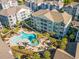 Aerial view of the community pool, palm trees, and a complex surrounded by lush greenery on a sunny day at 150 Ella Kinley Circle # 301, Myrtle Beach, SC 29588