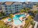 Aerial view of the community's uniquely shaped pool, lounge chairs, palm trees, and building architecture on a sunny day at 150 Ella Kinley Circle # 301, Myrtle Beach, SC 29588