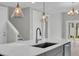 Modern kitchen island with stone countertop, stainless steel sink and stylish pendant lighting at 1545 Coastal Cove Ln, Calabash, NC 28467