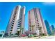 Condominium exterior featuring two high-rise buildings, palm trees, parking, and clear blue skies at 2500 N Ocean Blvd. # 102, Myrtle Beach, SC 29577