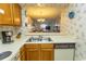 Kitchen with laminate countertops, stainless sink, wooden cabinets and floral wallpaper and open view to living area at 305 N Hillside Dr. # 206, North Myrtle Beach, SC 29582