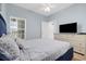 This bedroom features a blue bed, light blue walls, ceiling fan, and a large window with natural light at 3401 N Ocean Blvd. # 110, North Myrtle Beach, SC 29582